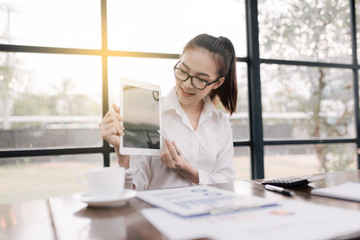 Fototapeta premium Portrait of smiling pretty young business woman in glasses sitting on workplace, graph, computer