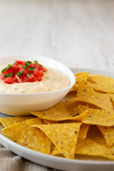 Homemade cheesy dip in a bowl, yellow tortilla chips, side view. Copy space.