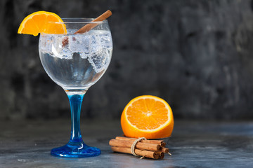 gin tonic on blue glass with orange and cinnamon