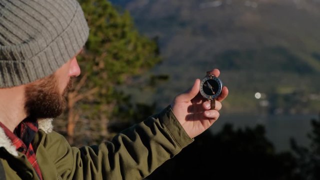 Close up on compass instrument in gloved hand . Mountain hiking trails. Fores trip concept.