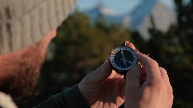 Close up on compass instrument in gloved hand . Mountain hiking trails. Fores trip concept.