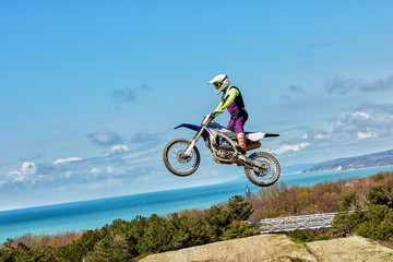 Naklejka na ściany i meble Extreme sports, motorcycle jumping. Motorcyclist makes an extreme jump against the sky.
