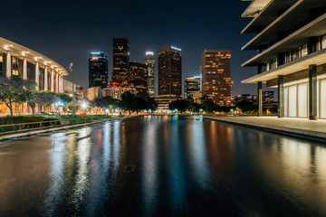 The downtown Los Angeles skyline at night, with the reflecting pool at the Department of Water and...