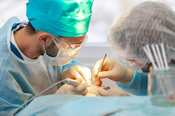 Baldness treatment. Hair transplant. Surgeons in the operating room carry out hair transplant...