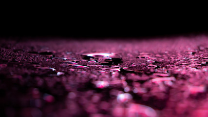 Dark background. Spilled liquid on the mirror surface, the reflection of neon lights, glare, blurred bokeh background. Neon, night view of the streets of a big city.