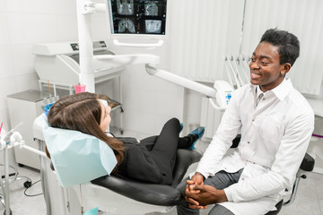 Obraz premium Young African male dentist with a patient. Woman in the dentist chair at dental clinic. Medicine, health, stomatology concept. dentist treating a patient.