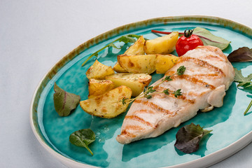 Grilled chicken fillet with fried potatoes. On light background