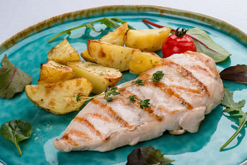 Grilled chicken fillet with fried potatoes. On light background