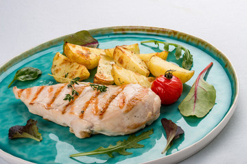 Grilled chicken fillet with fried potatoes. On light background