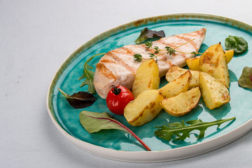 Grilled chicken fillet with fried potatoes. On light background