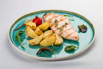 Grilled chicken fillet with fried potatoes. On light background