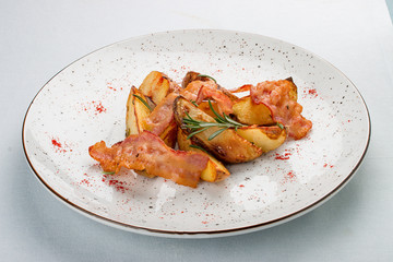 Fried potatoes with bacon and rosemary. On white background