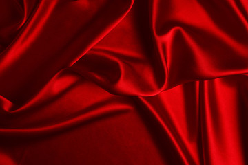 Red silk or satin luxury fabric texture can use as abstract background. Top view.