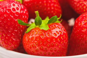 Red ripe strawberry in the white bowl, light background