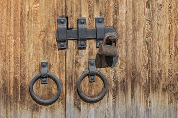 fragment of an old wooden door with a lock and ring-shaped door handles