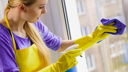 Girl cleaning window at home