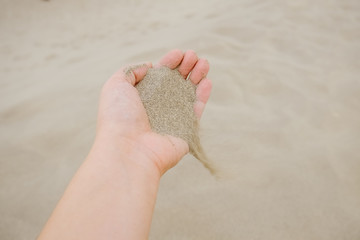 Sand flowing from a hand into the desert.