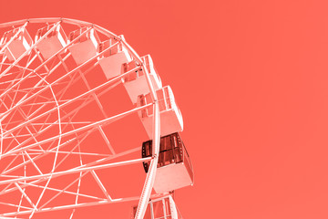 Close-up big white modern ferris wheel against clear sky on background in Kiev city center. One black gondola among other. One of a kind.Toned with trendy color 2019 coral © Kirill Gorlov