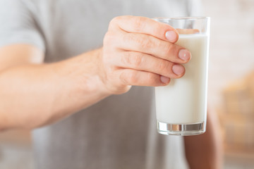Dairy products. Balanced nutrition. Closeup of glass of soy milk in man hand. Blur background.