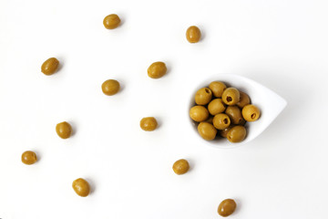 Olives without pits in a white plate isolated on white background, olives are scattered on the table