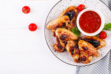 Baked chicken wings in the Asian style and tomatoes sauce on plate. Top view