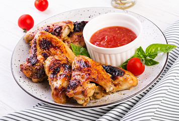 Baked chicken wings in the Asian style and tomatoes sauce on plate.