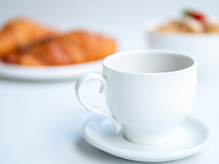 Breakfast with selective focus on the tea cup. Bokeh effect with porridge and croissants on background. Healthy food