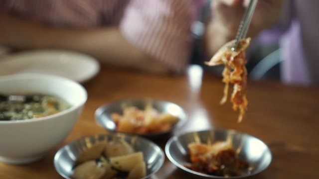 Using siver steel chopstick eating korean food kimchi side dishes