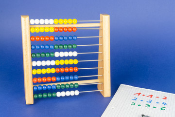 A slide rule with colorful balls and a calculating block, blue background and copy space