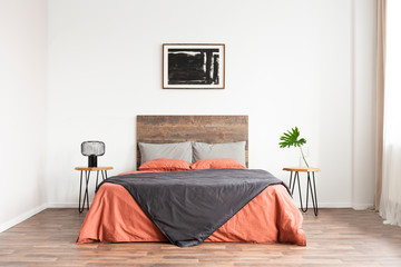 Minimal classic bedroom with wooden bed, coral linen sheets and black and white artwork