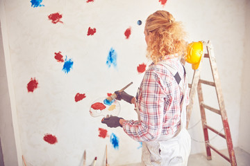Working woman plastering / painting walls inside the house.