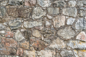 Stone wall texture. Colorful granite stone background. Old Vintage Stone Wall of Historical Medieval Castle in North Europe. 
