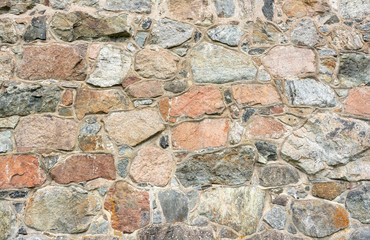 Stone wall texture. Colorful granite stone background. Old Vintage Stone Wall of Historical Medieval Castle in North Europe. 