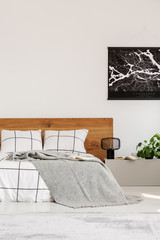 Copy space on white wall with black map in modern bedroom with king size bed with wooden headboard