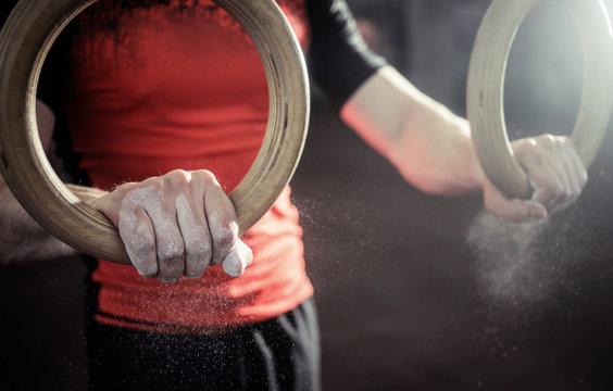 Sport. Muscle-up exercise young man workout at the gym on gymnastic rings with magnesia on the hands. Grop close-up view. - Powered by Adobe