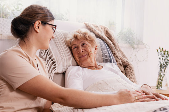 Elderly Woman In Hospital Bed With Social Worker Helping Her