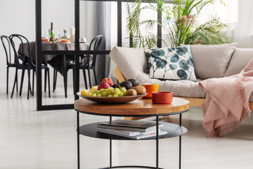 Comfortable beige scandinavian settee with patterned pillow in bright living room interior