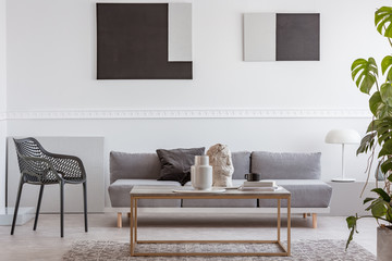 Knick knacks on elegant coffee table in front of grey sofa in luxury living room interior