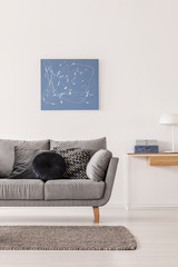 Blue abstract painting on white wall of fashionable living room interior with grey couch and console table