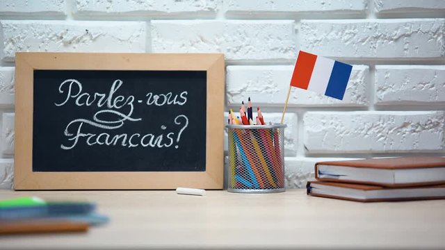 Do you speak French written on board, hand putting France flag in box, language