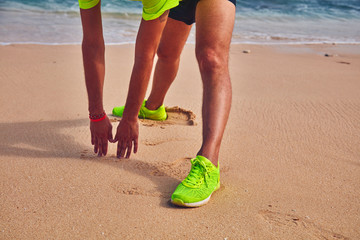 Sportsman stretching on a tropical sandy beach.