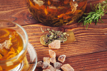 glass teapot with cup of black tea on wooden table
