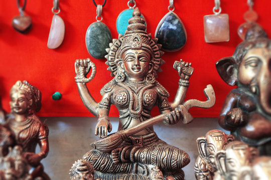 Bronze figure of the goddess of wisdom Saraswati on a red background in a souvenir shop in India.