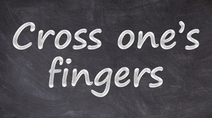 Cross one&rsquo;s fingers written on blackboard