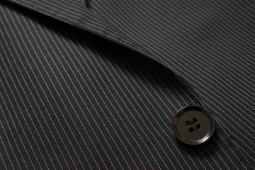 Detail of closeup of suit button on pin stripped cloth. Tailoring background