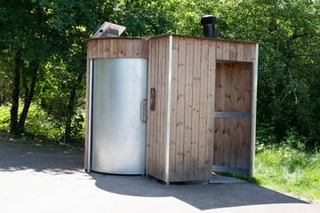 Unisex public dry toilet modern wooden outhouse outside in park