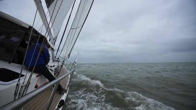 Sailing yachts in France with a sailor sitting on deck. Filmed in La Rochelle.
