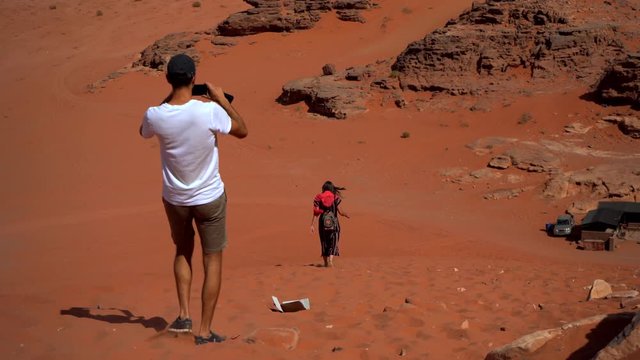 Mobile phone photographer. Tourist on the desert take phone pictures. Man is taking the landscape photos by smart phone.  Wadi Rum desert, Jordan