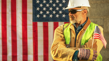 American builder looking sideways with stars and stripes flag in background, toned warm image