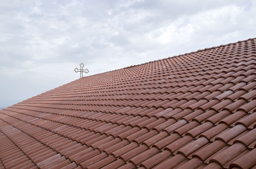 Metal cross on the roof of a church in Greece against sky